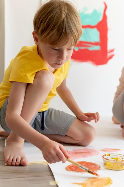 Tiro completo de menino pintando no papel