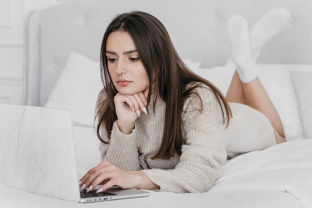 Foto grátis tiro completo de mulher na cama com laptop