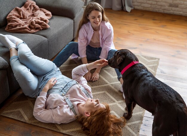 Tiro completo de mulheres e cachorro deitado no chão