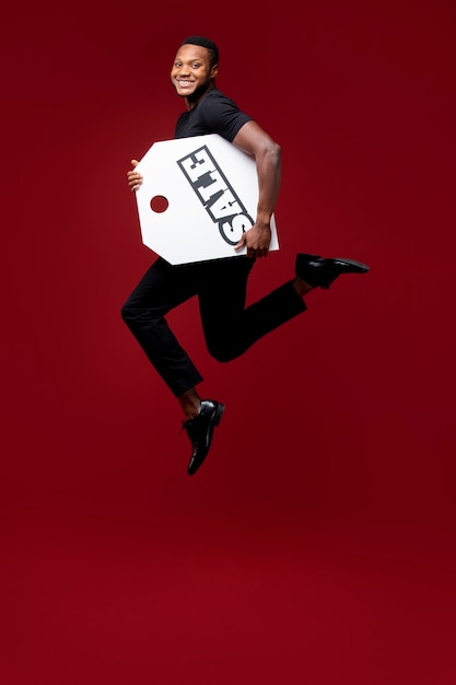 Foto grátis tiro completo do homem pulando com etiqueta de venda