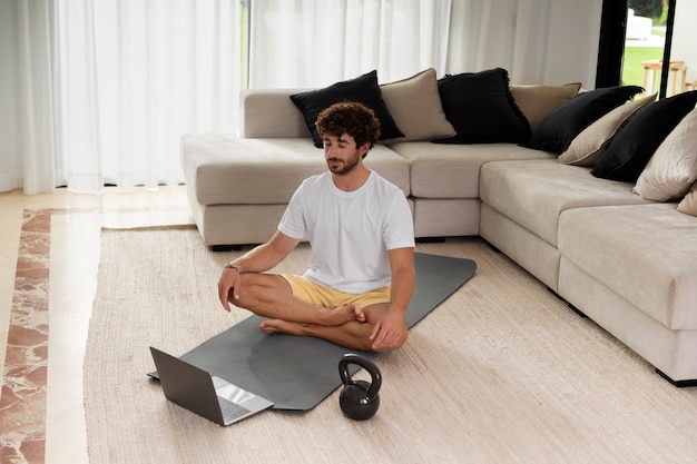 Foto grátis tiro completo homem meditando no tapete