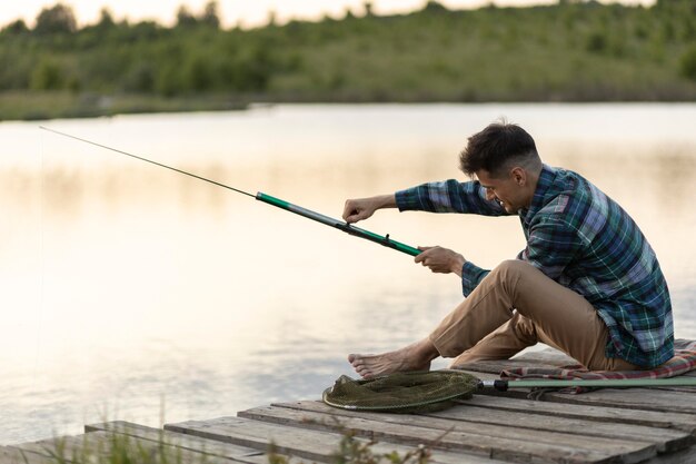 Tiro completo homem sentado e pescando