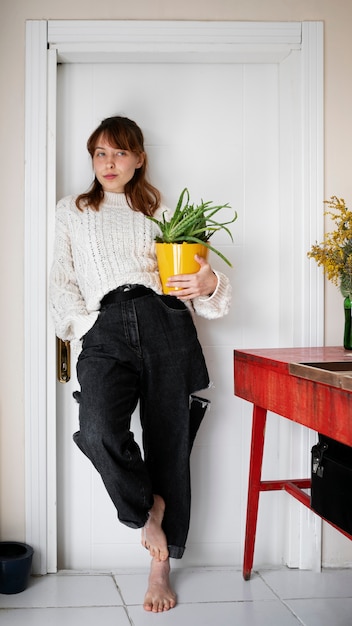 Foto grátis tiro completo jovem segurando a planta