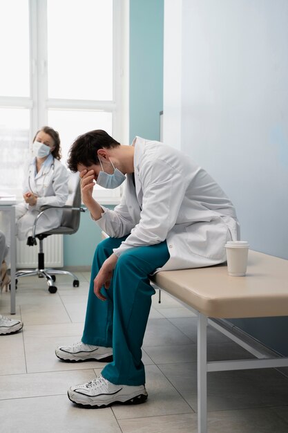 Tiro completo médico cansado sentado