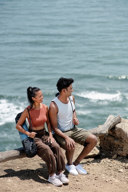 Tiro completo pessoas sentadas à beira-mar com tapetes de ioga