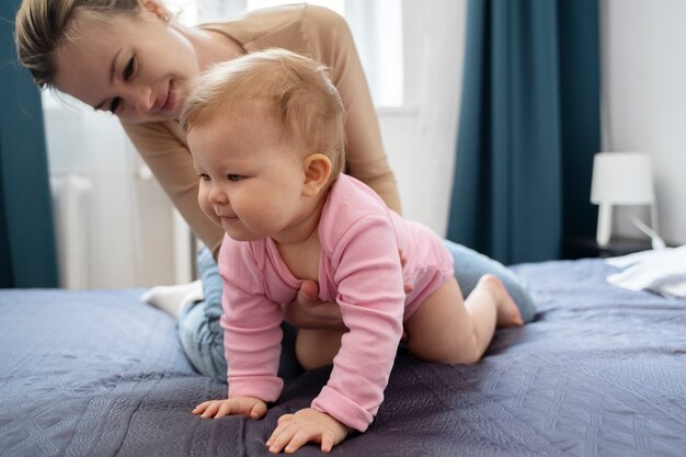 Tiro completo sorridente mãe e bebê na cama