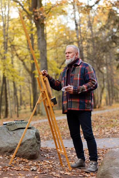 Foto grátis tiro completo velho pintando ao ar livre