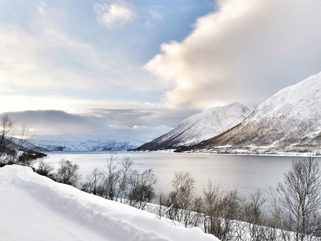 Tiro de alto ângulo de um lago por colinas cobertas de neve em kattfjorden, noruega capturado durante o inverno Foto Premium
