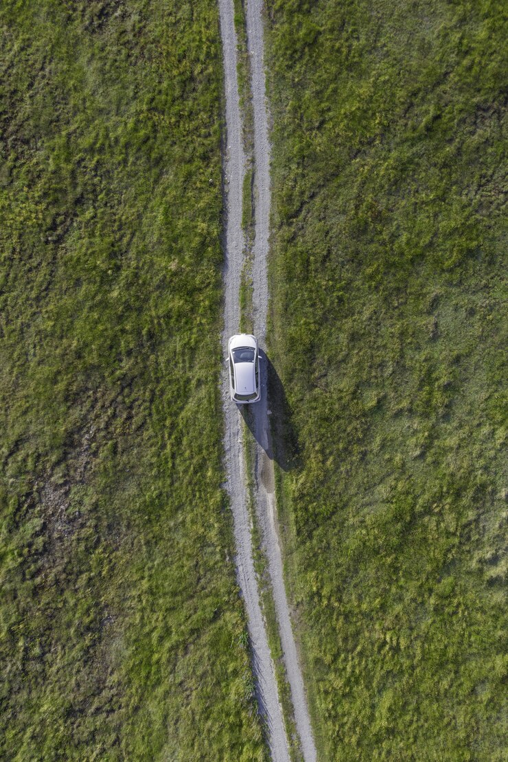 Foto grátis tiro de alto ângulo vertical de um carro branco andando pelo caminho no vale verde
