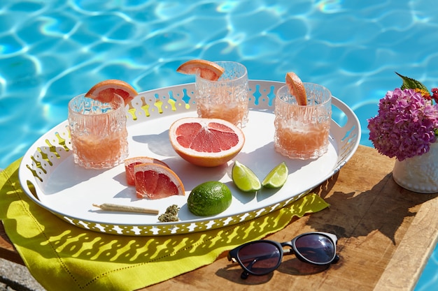 Foto grátis tiro de ângulo alto closeup de uma bandeja com cocktails de toranja perto da piscina