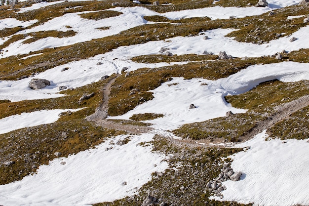 Tiro de ângulo alto de texturas de terra parcialmente cobertas de neve nos Alpes italianos