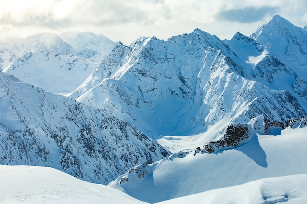 Tiro de ângulo alto de uma bela cordilheira coberta de neve sob o céu nublado