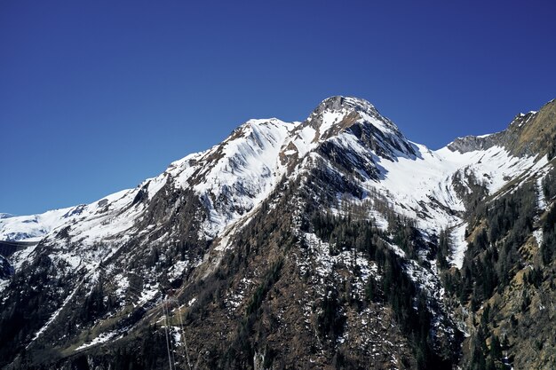 Tiro de ângulo baixo bonito de uma montanha com neve cobrindo o pico e o céu na