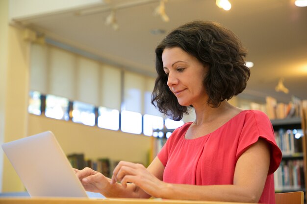 Tiro de ângulo baixo da mulher focada digitando no laptop