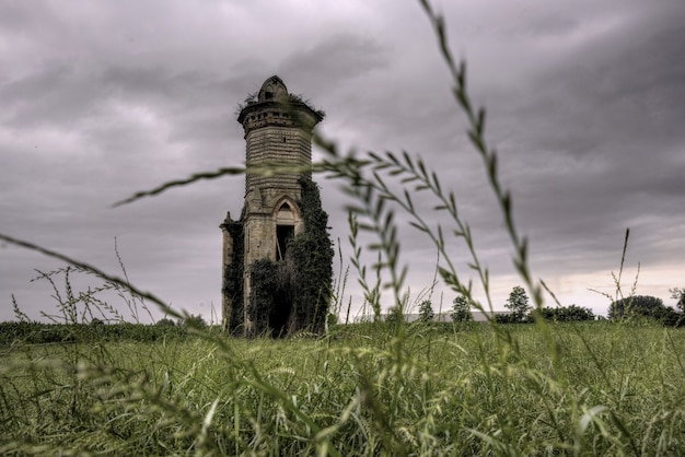 Tiro de ângulo baixo de um edifício antigo no meio de um campo sob o céu sombrio