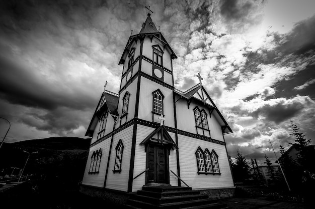 Tiro de ângulo baixo de uma igreja sob um céu nublado em preto e branco