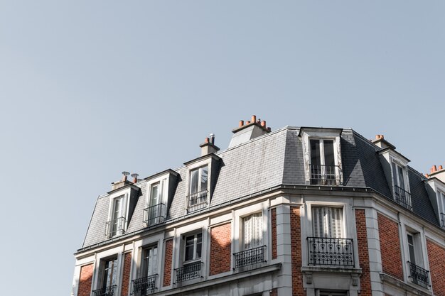 Tiro de ângulo baixo do telhado de um belo edifício com varandas em Paris