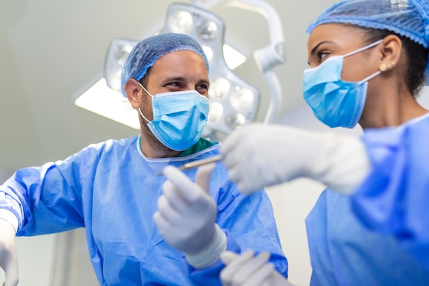 Tiro de ângulo baixo na sala de cirurgia Assistente entrega instrumentos aos cirurgiões durante a operação Cirurgiões realizam a operação Médicos profissionais realizando cirurgia