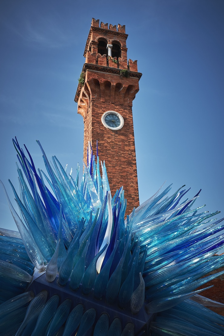 Foto grátis tiro de ângulo baixo vertical de uma torre e uma escultura azul em murano, itália