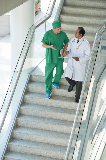 Tiro de dois médicos descendo as escadas do hospital