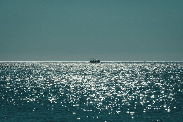 Tiro de longo alcance de um barco navegando no mar, refletindo o sol