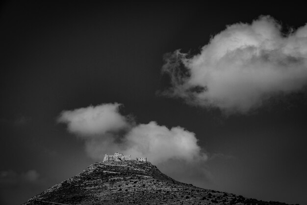 Tiro de longo alcance de uma montanha com casas no topo em preto e branco