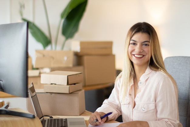 Tiro de retrato de trabalhador de escritório feminino feliz olhando para a câmera e sorrindo. Empresária de sucesso trabalhando no escritório. Sucesso, negócios, conceito de juventude