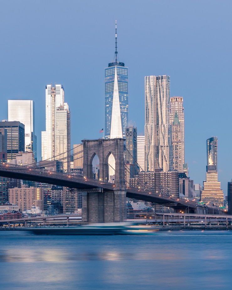 Foto grátis tiro distante vertical da ponte do brooklyn sobre o corpo de água perto de arranha-céus em nova york