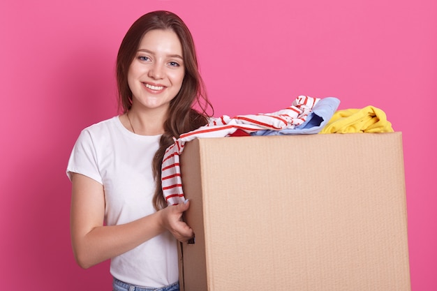 Tiro horizontal de carrinhos femininos sorrindo perto de ambos com roupas reutilizáveis para pessoas pobres