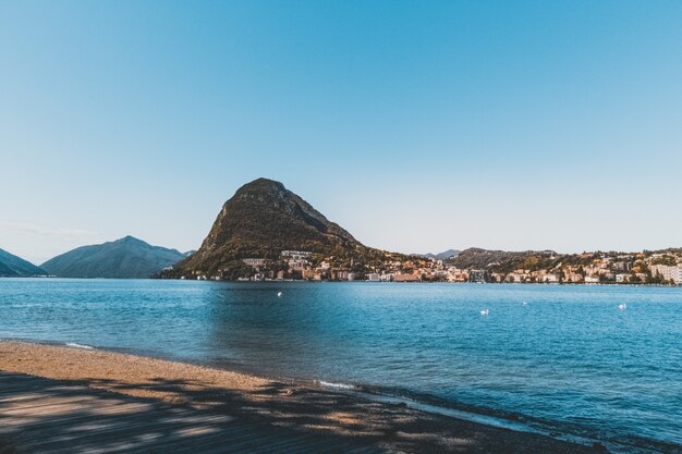 Tiro horizontal do lindo mar azul, rodeado por montanhas rochosas e edifícios de concreto