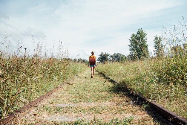 Tiro longo, de, mulher caminhando, ligado, estrada ferro