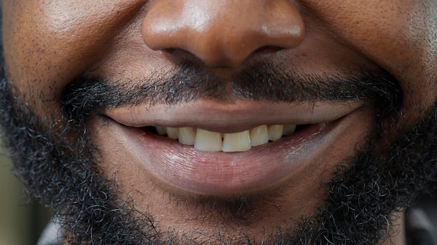 Tiro macro do homem movendo os lábios na frente da câmera e sorrindo, mostrando expressão facial positiva. pessoa saudável com pele natural mostrando sorriso sincero, barba curta. emoções autênticas.