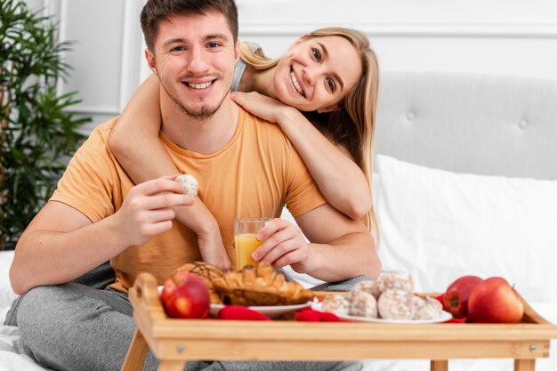 Tiro médio casal feliz com café da manhã na cama