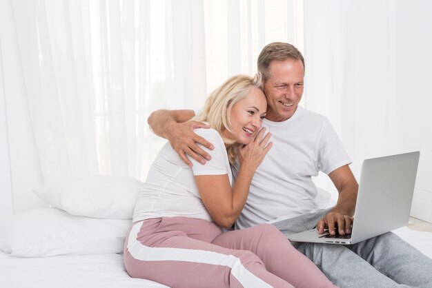 Tiro médio casal feliz com laptop no quarto