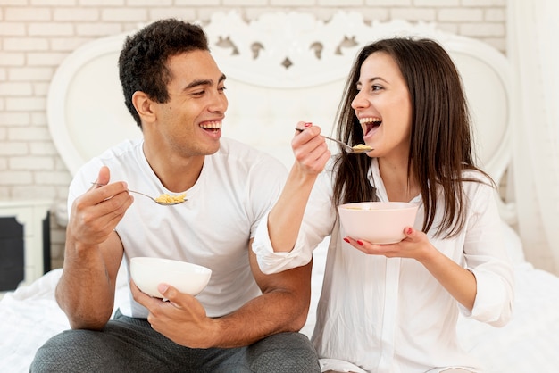 Tiro médio casal feliz comendo cereais juntos
