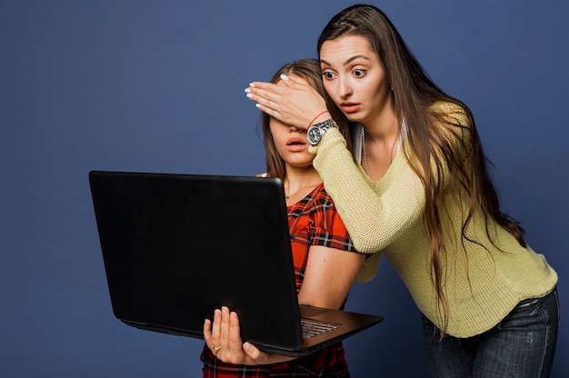 Tiro médio chocado meninas com laptop