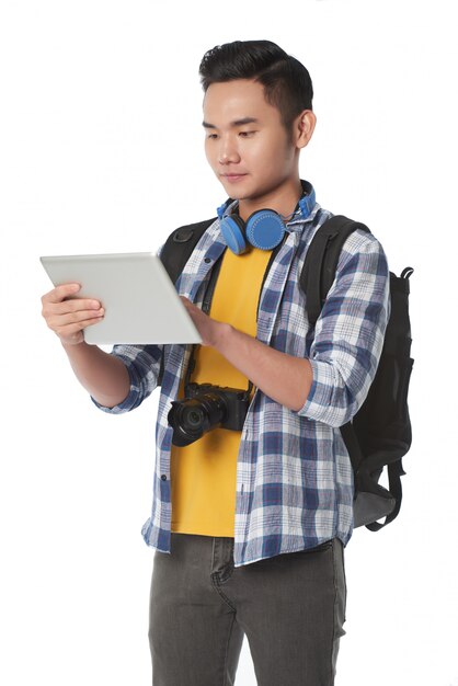 Tiro médio de jovem com mochila usando o tablet PC