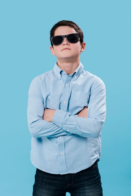 Tiro médio do menino moderno posando com óculos de sol