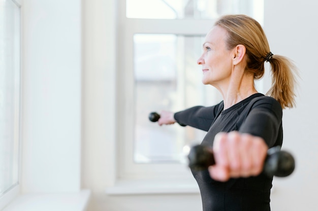 Tiro médio feminino segurando halteres