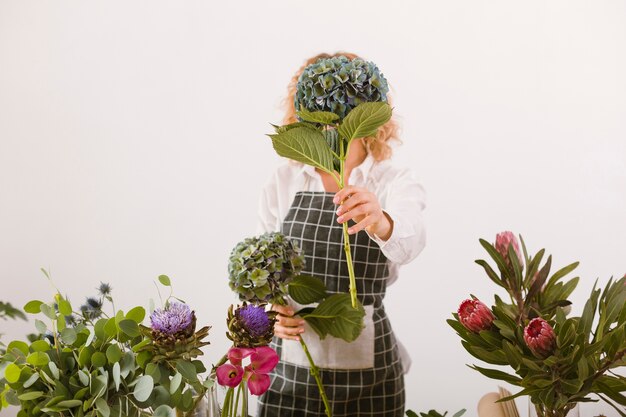 Tiro médio florista cobrindo o rosto com buquê