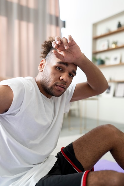 Tiro médio homem cansado sentado no tapete