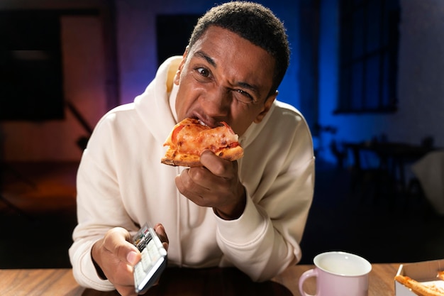 Tiro médio homem comendo pizza