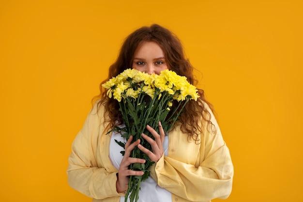 Foto grátis tiro médio jovem posando com flores