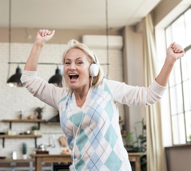 Tiro médio mulher feliz com fones de ouvido dentro de casa