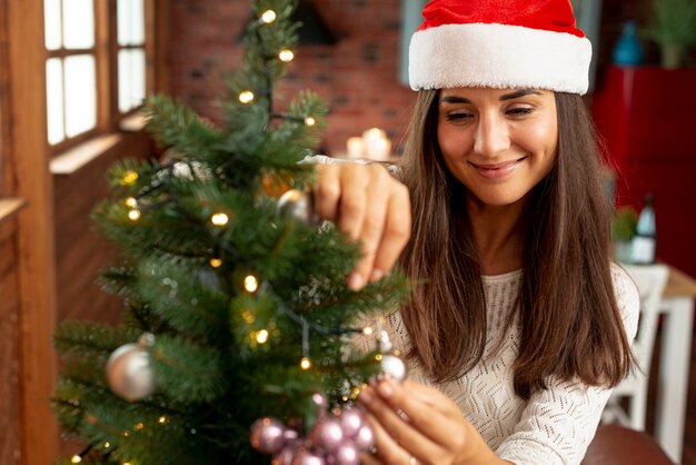 Tiro médio mulher feliz decorando a árvore de Natal