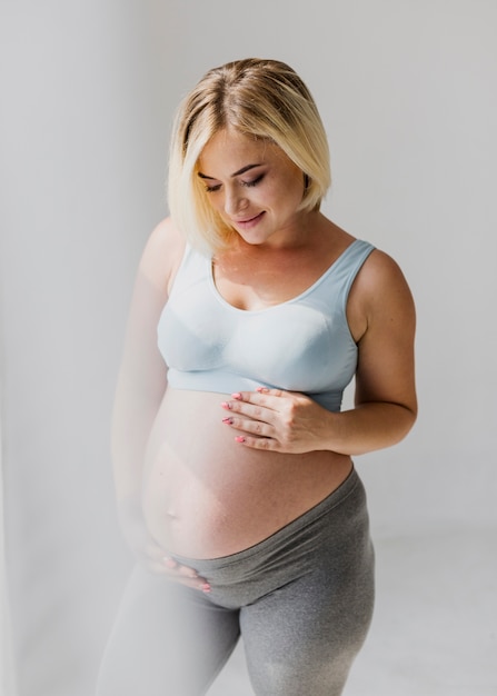 Foto grátis tiro médio, mulher grávida, olhando baixo