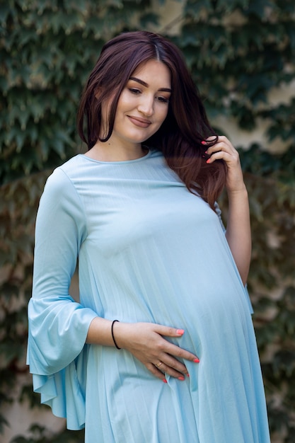 Tiro médio, mulher jovem grávida, posar, ao ar livre