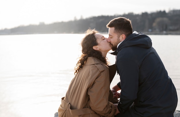 Tiro médio, par beijando, ao ar livre