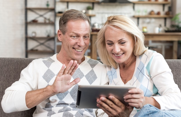 Tiro médio sorridente casal segurando um tablet