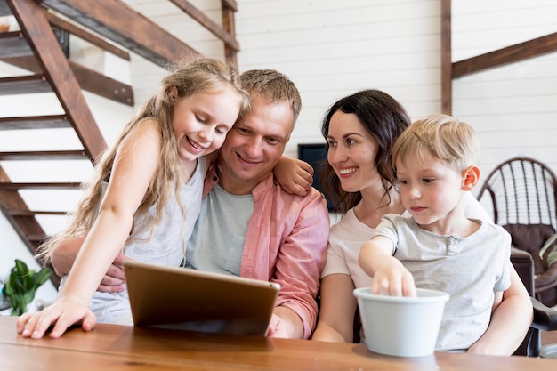 Tiro médio sorridente família olhando para tablet